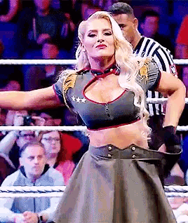 a woman is standing in a wrestling ring with her arms outstretched in front of a crowd .