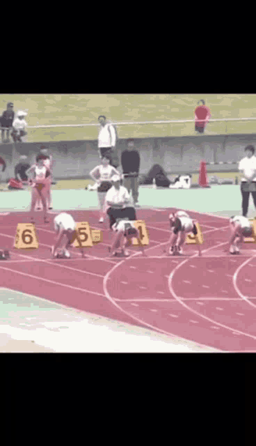a group of people are getting ready to run on a track with numbers 6 5 and 1 on the blocks
