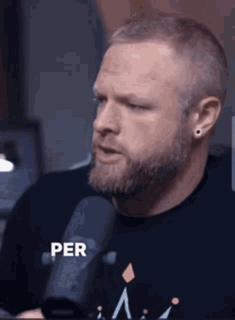 a man with a beard is talking into a microphone and the word per is on the bottom right