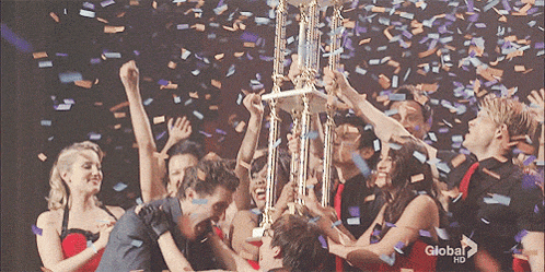 a group of people holding a trophy with confetti falling and a global hd logo in the background