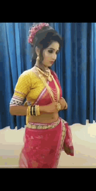 a woman is wearing a red saree and a yellow top .