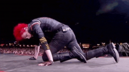 a man with red hair is crawling on a stage .