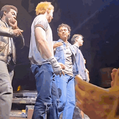 a group of men are standing on a stage and one of them has a bandaged hand