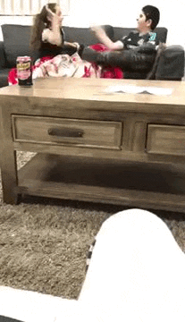 a boy and a girl are sitting on a couch in front of a coffee table in a living room .