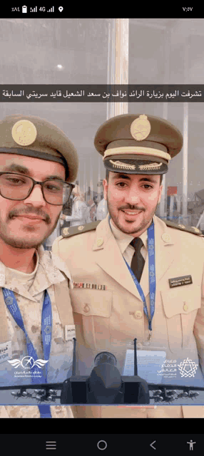two men in military uniforms pose for a photo with a plane in the background