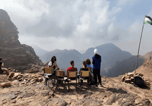 a group of people sit in chairs on top of a rocky hillside
