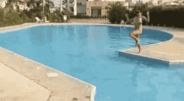 a woman is jumping into a large swimming pool