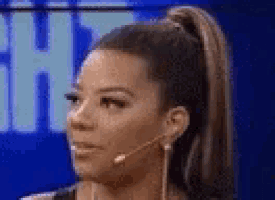 a woman is wearing a microphone and a ponytail .