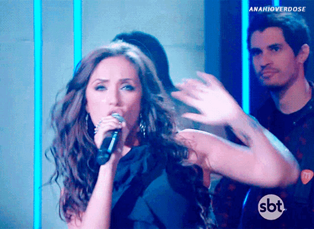 a woman singing into a microphone with the sbt logo in the background