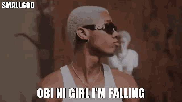 a man wearing sunglasses and a white tank top is saying `` obi ni girl i 'm falling `` .