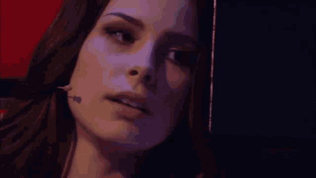 a close up of a woman 's face in a dark room smiling .