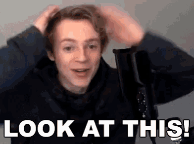 a young man is holding his hair in front of a microphone and says `` look at this ! ''