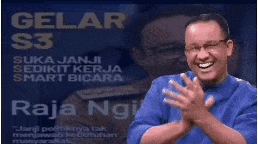 a man applauds in front of a poster that says di gelar s3 suka janji sedikit kerja smart bicara raja ngi
