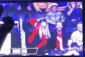 a group of people sitting in a stadium watching a game on a television screen .