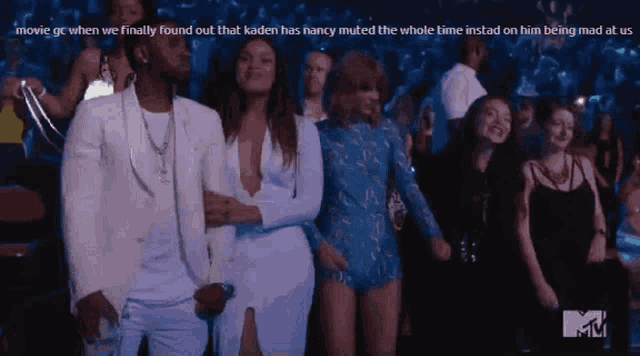 a man in a white suit stands next to a woman in a blue dress at a party