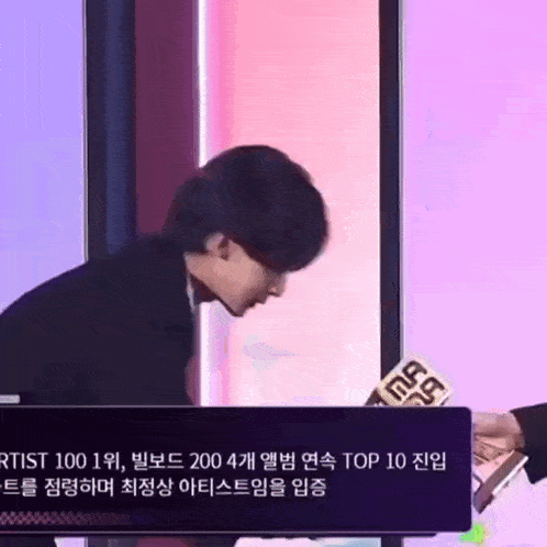 a man is standing in front of a microphone and a sign that says top 10 on it .