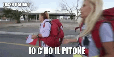 two women with backpacks are walking down a street and one of them says io c ' ho il pitone