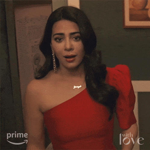a woman is covering her mouth with her hand while wearing a red dress and earrings from prime with love