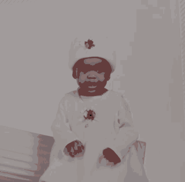 a baby girl wearing a white dress and a white hat