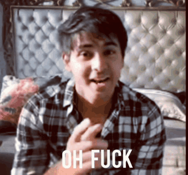 a man in a plaid shirt says " oh fuck " in front of a bed