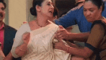a woman in a white sari is being held by a group of people .