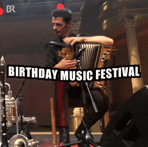 a man playing an accordion in front of a birthday music festival banner