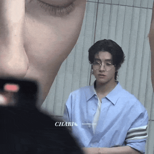 a man wearing glasses and a blue shirt is being photographed by a chabi fan