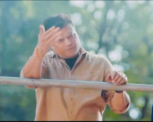 a man in a tan shirt is standing next to a metal railing