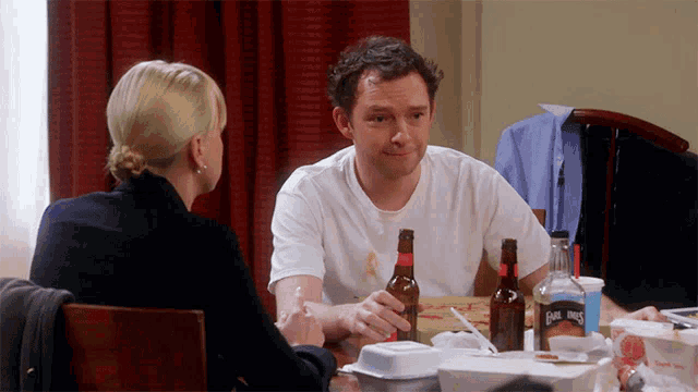a man sits at a table with two bottles of carl jones on it