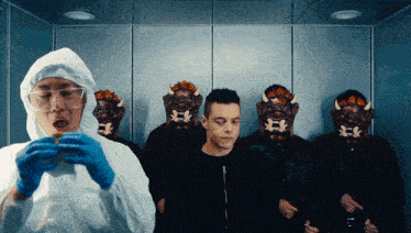 a man in a protective suit is eating a hamburger in front of a group of men wearing masks
