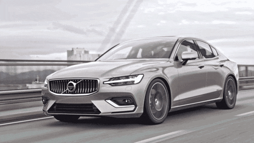 a volvo car is driving on a highway with a bridge in the background