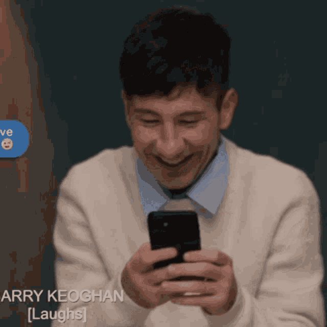 a man is laughing while looking at his phone
