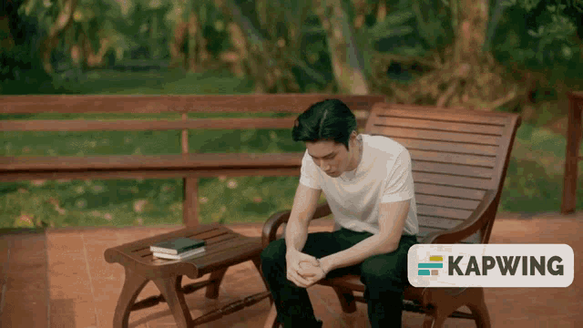 a man sits on a wooden chair with a kapwing logo in the background