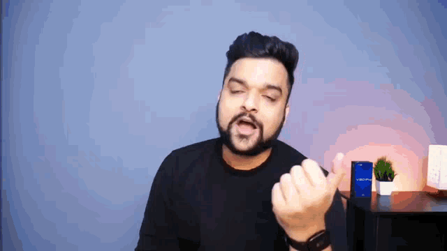 a man with a beard is giving a thumbs up while standing in front of a blue wall .