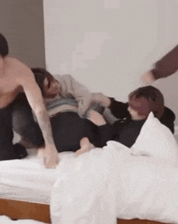 a man without a shirt is laying on a bed with a woman .
