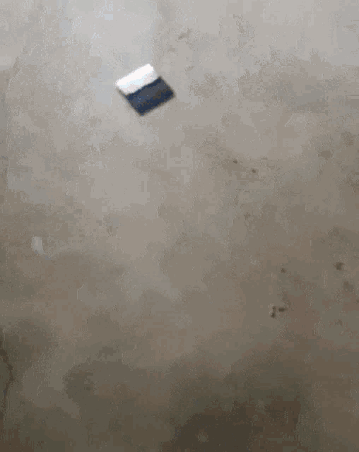 a piece of paper is floating in the air on a concrete floor .