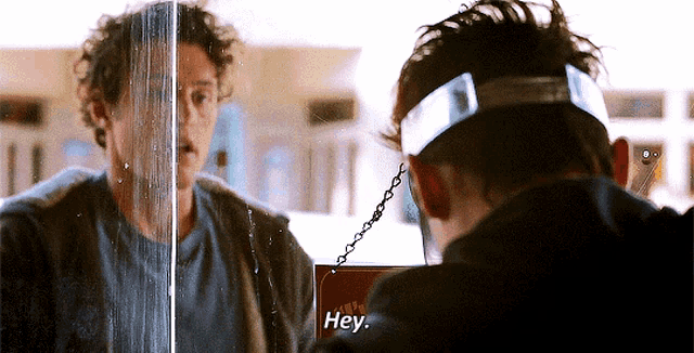 a man talking to himself in a mirror with a sign that says hey