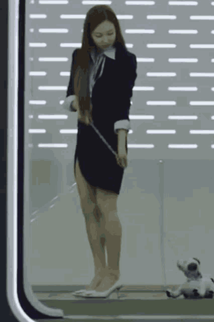 a woman in a suit is standing next to a stuffed animal on a leash