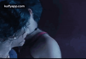 a woman is crying in a dark room while a man looks on .