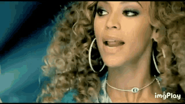 a woman with curly hair and hoop earrings is wearing a necklace and earrings .