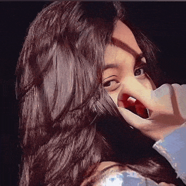 a girl with long hair is covering her mouth with her hand