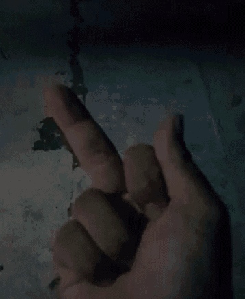 a person 's hand is making a middle finger gesture in the dark