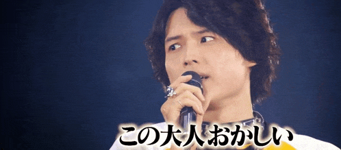 a man singing into a microphone with foreign writing on the bottom