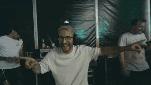 a man wearing headphones and a white t-shirt is pointing at something