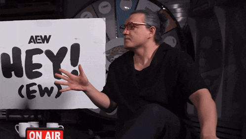 a man is sitting in front of a sign that says hey