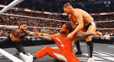 wrestlers in a ring with a sign that says raw in the background