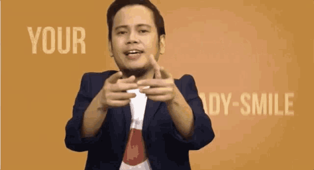 a man in a suit is pointing at the camera with the words your ready smile behind him