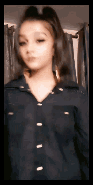 a woman in a black shirt stands in front of a window