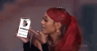a woman with red hair is holding a cell phone with a picture of a man on it .