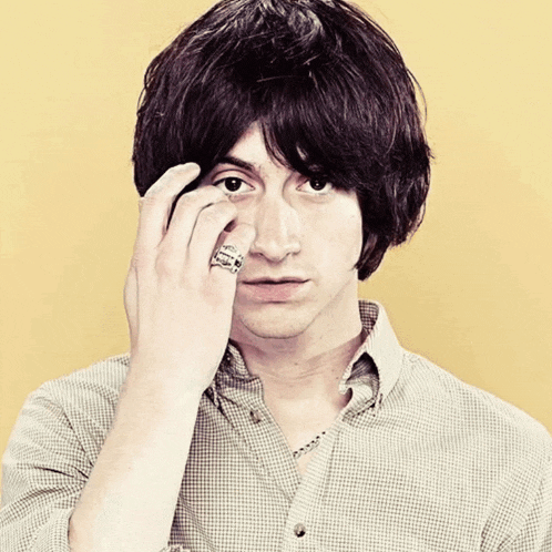 a man with a skull ring on his finger looks at the camera